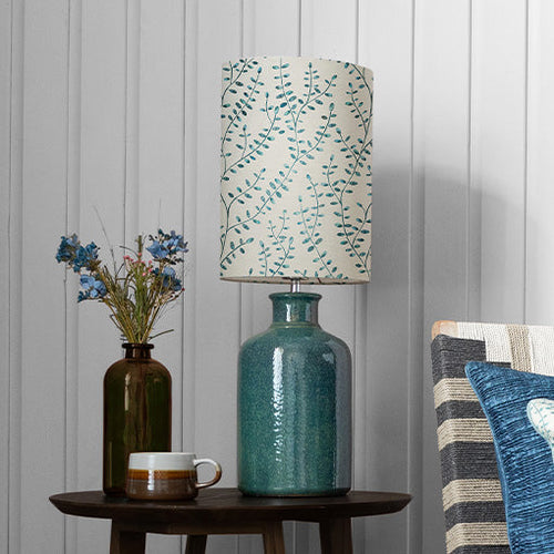 A blue table lamp with a floral lamp shade design stood on a wooden side table.