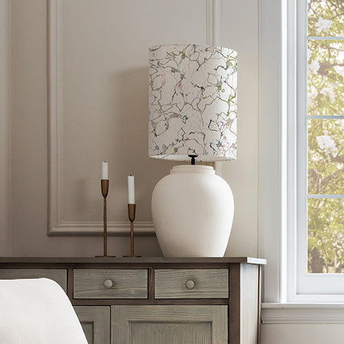 A ceramic lamp with a minimalist style lamp shade displayed on a wooden console table.