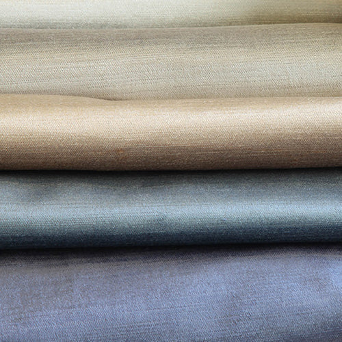 Neutral coloured plain and textured fabrics folded and displayed in a single pile.